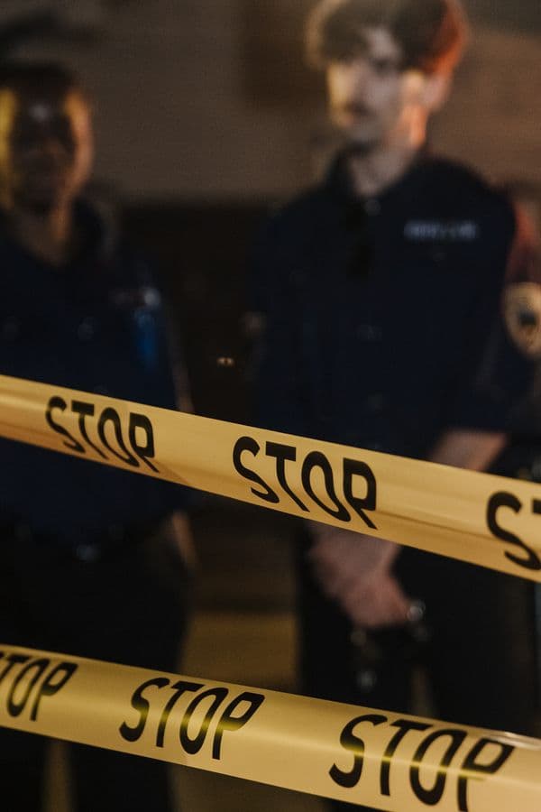 Police officers standing behind crime scene tape