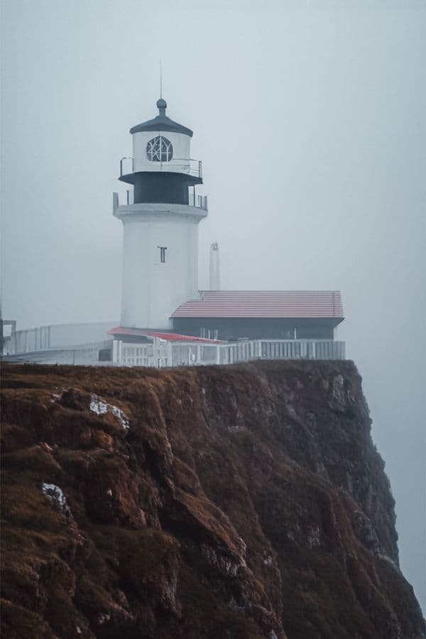 Lighthouse on a cliff shrouded in fog