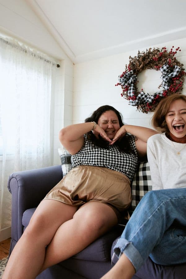 Two friends laughing together on a sofa
