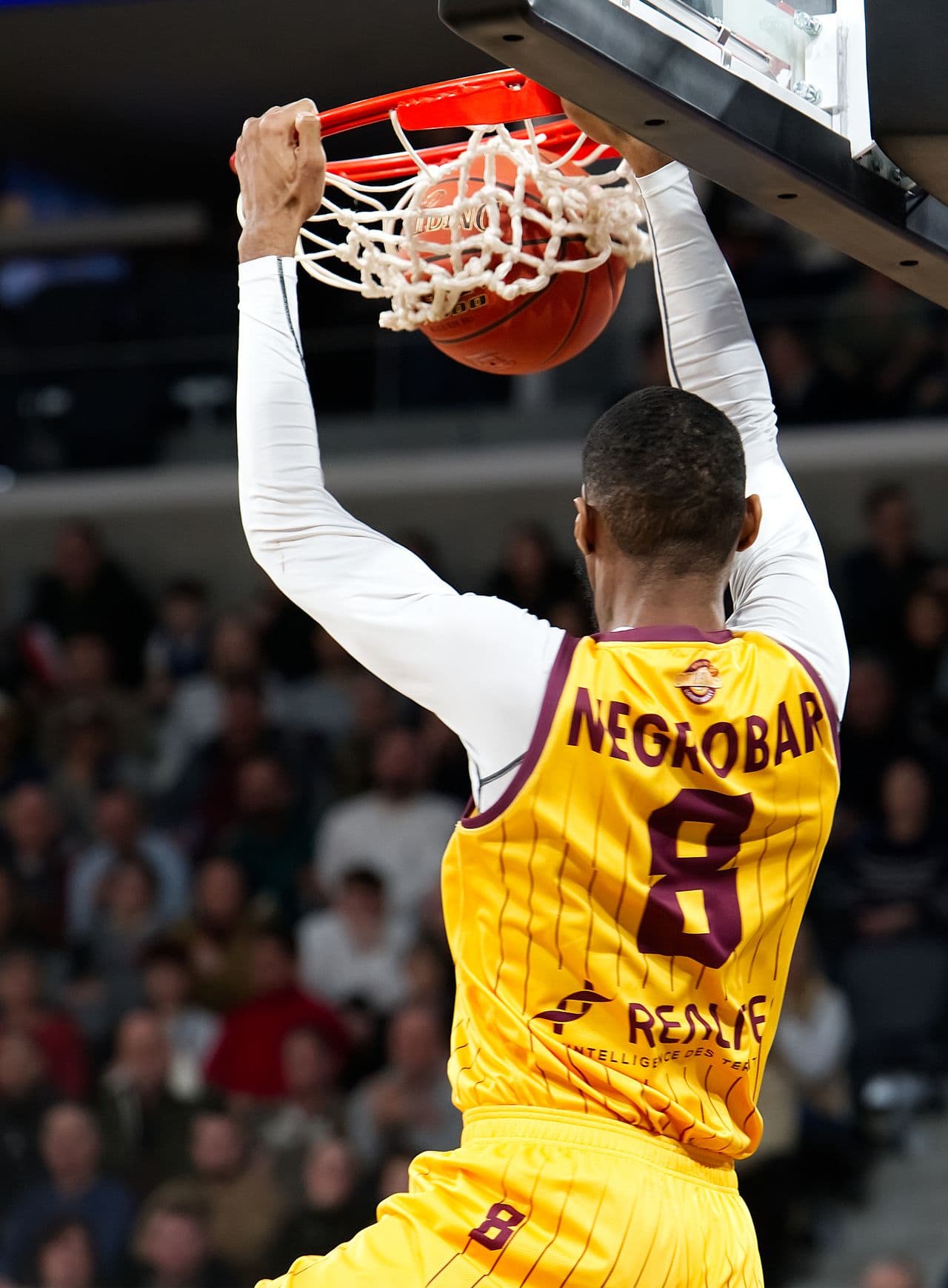 Basketball player hanging on the rim after a dunk