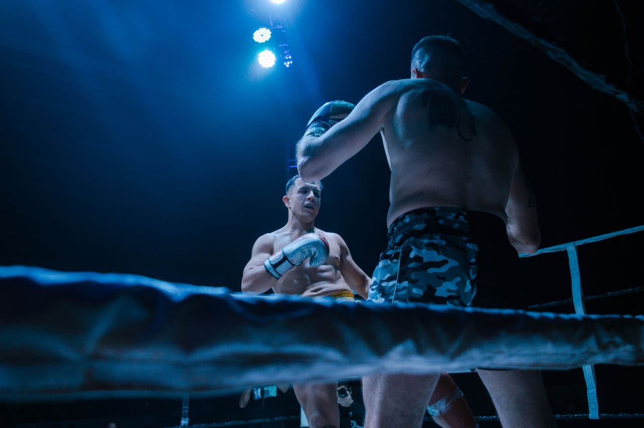 Two fighters exchanging blows under ring lights