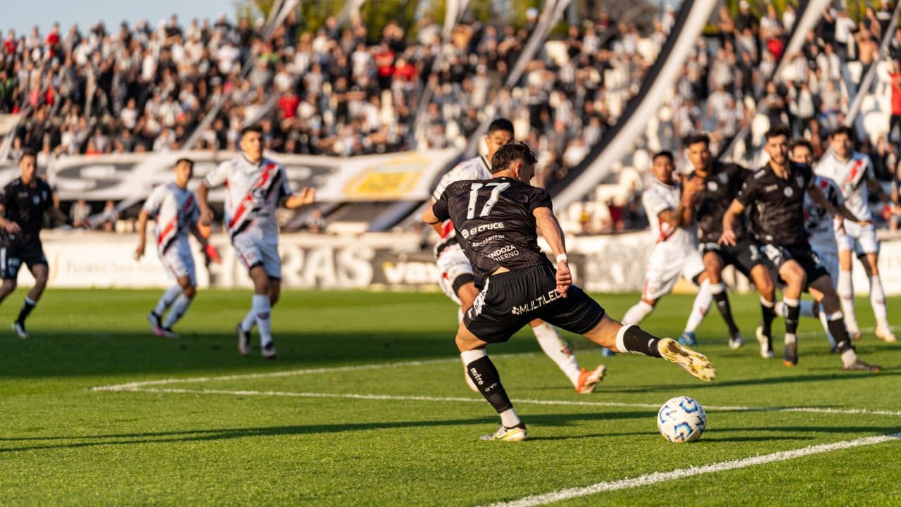 Footballer striking the ball in front of a packed stand