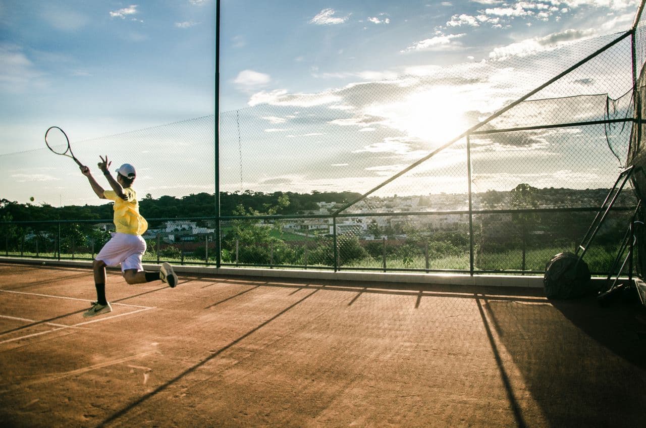 Tennis player leaping into a forehand at sunset